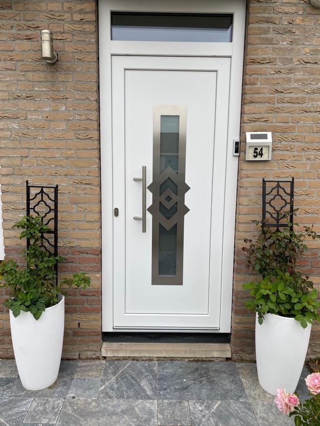 Witte kunststof voordeur met decoratief glaspaneel en bovenlicht, geplaatst in een bakstenen gevel van een moderne woning in Nederland.